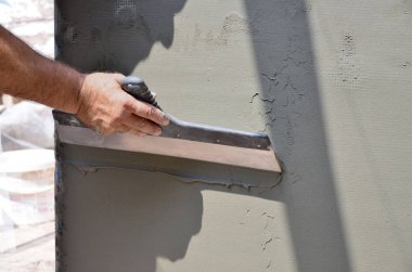 Ev yenilenen araçları sıvama duvar ile eski bir işçi elleri. Sıvacı yenilenen açık duvar ve spatula ve alçı ile köşeleri. Duvar izolasyonu. İnşaat bitirme işleri