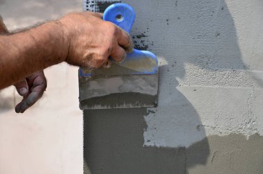 Ev yenilenen araçları sıvama duvar ile eski bir işçi elleri. Sıvacı yenilenen açık duvar ve spatula ve alçı ile köşeleri. Duvar izolasyonu. İnşaat bitirme işleri