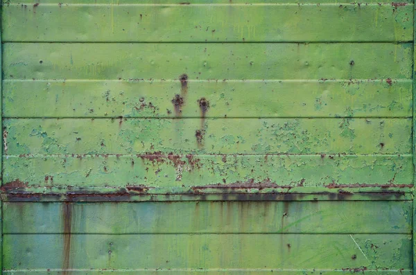 Texture of an old green metal wall with significant damage from exposure to unfavorable weather conditions and dampness