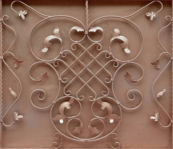 The texture of the bronze metal gate with a beautiful floral pattern of forged metal