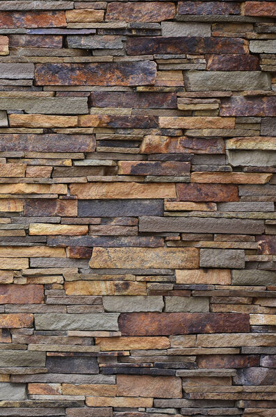 Texture of a stone wall from long and rough stones of different sizes and tones