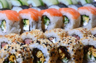 Birçok rulo suşi kümesi bir makro çekim'de bir tabloda bir suşi bar mutfak ahşap kesme tahtası üzerinde yer alır. Japon mutfağının geleneksel yemeği