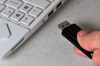 Bir erkek el Siyah kompakt Usb kart beyaz netbook tarafında karşılık gelen bir girdi ekler. Adam bellek ve dijital veri depolamak için modern teknolojiler kullanır