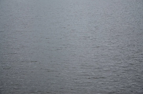 The texture of dark river water under the influence of wind, imprinted in perspective. Horizontal image