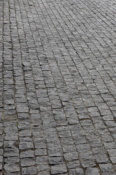 The texture of the paving slab (paving stones) of many small stones of a square shape under bright sunlight