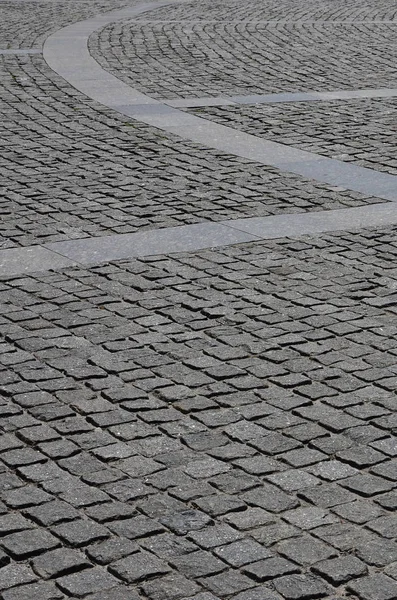 The texture of the paving slab (paving stones) of many small stones of a square shape under bright sunlight