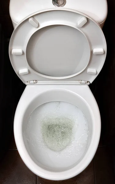 一张白色陶瓷马桶在洗涤过程中的照片 用自动冲洗装置纠正需要的陶瓷卫生洁具 — 图库照片