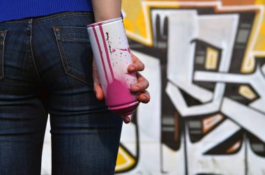 Bir kızın elini sprey boya ile fotoğrafı grafiti duvar arka plan üzerinde elinde kutular. Sokak sanatı ve sprey boya kullanımı kavramı. Graffiti sanat Dükkanı arka plan görüntüsü