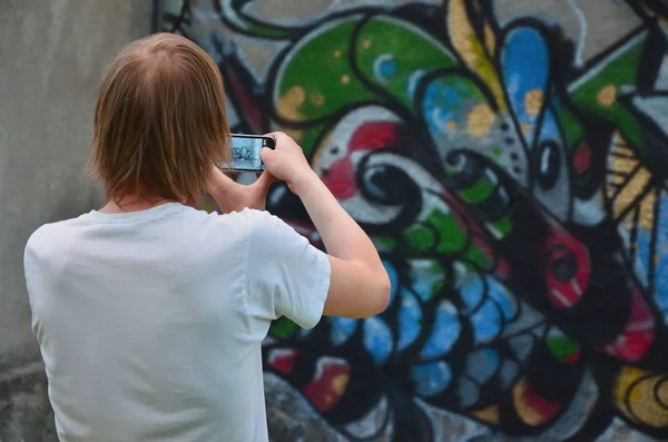 콘크리트 낙서를 그리기 남자는 스마트폰에 그림의 사진을 찍는다 행위의 — 스톡 사진