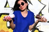 Картина, постер, плакат, фотообои "portrait of an emotional young girl with black hair and piercings. photo of a girl with aerosol paint cans in hands on a graffiti wall background. the concept of street art and use of aerosol paints", артикул 190940092