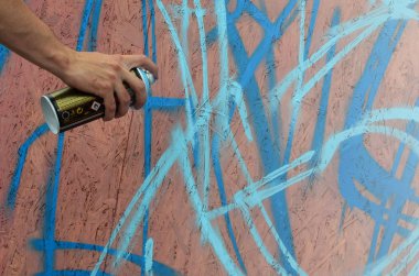 Bir el bir sprey ile yeni bir grafiti duvara çekiyor olabilir. Bir ahşap duvar yakın çekim bir grafiti çizim işlemi fotoğrafı. Sokak sanatı ve yasadışı vandalizm kavramı
