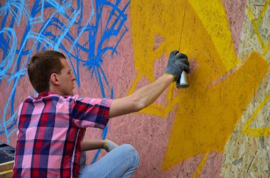 Bir genç Kızıl saçlı grafiti sanatçısı yeni bir graffiti duvar boyar. Bir duvara yakın çekim bir grafiti çizim işlemi fotoğrafı. Sokak sanatı ve yasadışı vandalizm kavramı