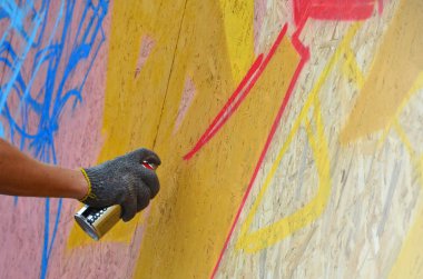 Bir el bir sprey ile yeni bir grafiti duvara çekiyor olabilir. Bir ahşap duvar yakın çekim bir grafiti çizim işlemi fotoğrafı. Sokak sanatı ve yasadışı vandalizm kavramı