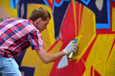 Bir genç Kızıl saçlı grafiti sanatçısı yeni bir graffiti duvar boyar. Bir duvara yakın çekim bir grafiti çizim işlemi fotoğrafı. Sokak sanatı ve yasadışı vandalizm kavramı