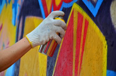 Bir el bir sprey ile yeni bir grafiti duvara çekiyor olabilir. Bir ahşap duvar yakın çekim bir grafiti çizim işlemi fotoğrafı. Sokak sanatı ve yasadışı vandalizm kavramı