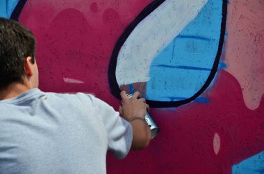 Bir genç grafiti sanatçısı yeni bir graffiti Duvar boyar. Bir duvara yakın çekim bir grafiti çizim işlemi fotoğrafı. Sokak sanatı ve yasadışı vandalizm kavramı