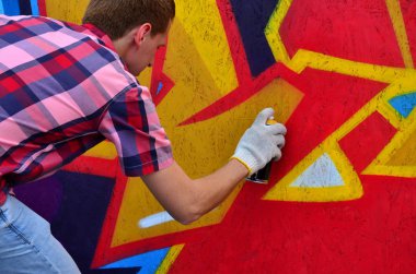 Bir genç Kızıl saçlı grafiti sanatçısı yeni bir graffiti duvar boyar. Bir duvara yakın çekim bir grafiti çizim işlemi fotoğrafı. Sokak sanatı ve yasadışı vandalizm kavramı
