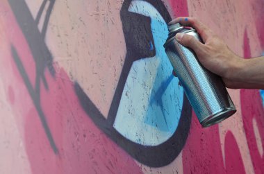 Bir el bir sprey ile yeni bir grafiti duvara çekiyor olabilir. Bir ahşap duvar yakın çekim bir grafiti çizim işlemi fotoğrafı. Sokak sanatı ve yasadışı vandalizm kavramı