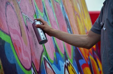 Bir genç Kızıl saçlı grafiti sanatçısı yeni bir graffiti duvar boyar. Bir duvara yakın çekim bir grafiti çizim işlemi fotoğrafı. Sokak sanatı ve yasadışı vandalizm kavramı