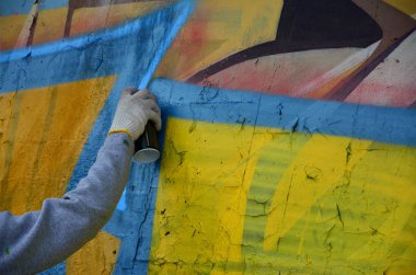 Bir el bir sprey ile yeni bir grafiti duvara çekiyor olabilir. Bir beton duvara yakın çekim bir grafiti çizim işlemi fotoğrafı. Sokak sanatı ve yasadışı vandalizm kavramı