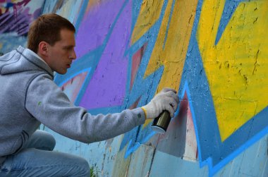 Bir genç Kızıl saçlı grafiti sanatçısı yeni bir graffiti duvar boyar. Bir duvara yakın çekim bir grafiti çizim işlemi fotoğrafı. Sokak sanatı ve yasadışı vandalizm kavramı