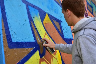 Bir genç Kızıl saçlı grafiti sanatçısı yeni bir graffiti duvar boyar. Bir duvara yakın çekim bir grafiti çizim işlemi fotoğrafı. Sokak sanatı ve yasadışı vandalizm kavramı