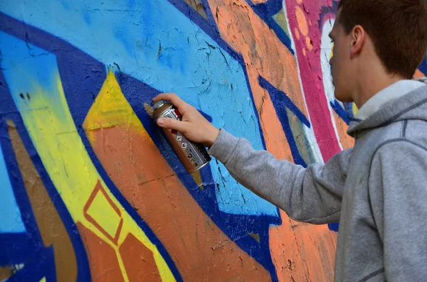 若い赤毛のグラフィティ アーティストは 新しい落書きの壁を描画します 壁のクローズ アップにらくがきのプロセスの写真 ストリート アートや違法な破壊行為の概念 — ストック写真