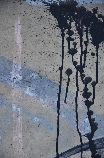 A photograph of a close-up of black paint spots on a concrete wall. Pouring paint on the wall in random order. The concept of graffiti and street art culture