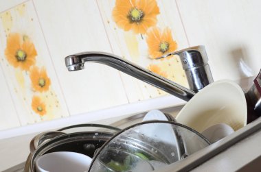 Kirli bulaşıklar ve yıkanmamış mutfak aletleri mutfak lavabosunu doldurdu.