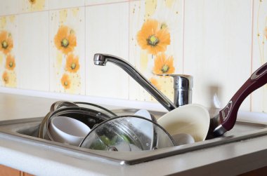 Kirli bulaşıklar ve yıkanmamış mutfak aletleri mutfak lavabosunu doldurdu.