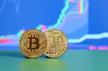 Grafikteki konumu büyüme gösteriyor ekranının arka planına yeşil yüzey üzerinde iki altın bitcoins yalan
