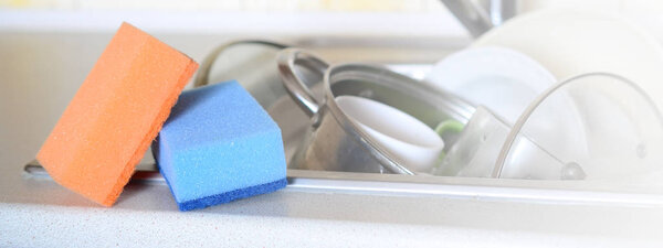 A few sponges lie on the background of the sink with dirty dishes