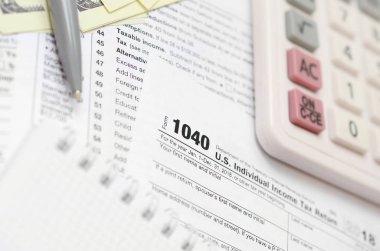 Kalem, defter, hesap makinesi ve dolar faturaları yalanlar üzerine vergi 1040 ABD bireysel gelir vergisi beyannamesi formu var. Vergi ödemek için zaman