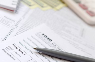 Kalem, defter, hesap makinesi ve dolar faturaları yalanlar üzerine vergi 1040 ABD bireysel gelir vergisi beyannamesi formu var. Vergi ödemek için zaman
