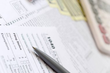 Kalem, defter, hesap makinesi ve dolar faturaları yalanlar üzerine vergi 1040 ABD bireysel gelir vergisi beyannamesi formu var. Vergi ödemek için zaman