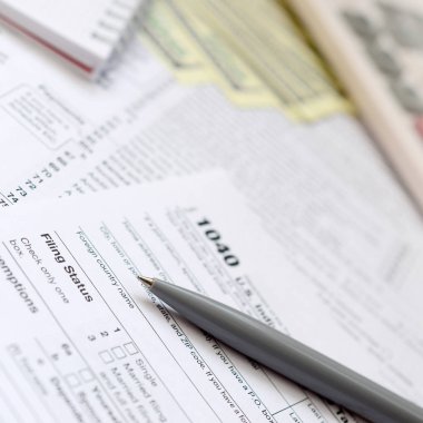 Kalem, defter, hesap makinesi ve dolar faturaları yalanlar üzerine vergi 1040 ABD bireysel gelir vergisi beyannamesi formu var. Vergi ödemek için zaman