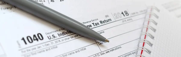 笔和笔记本是位于税表1040美国个人所得税的回报 纳税时间 — 图库照片