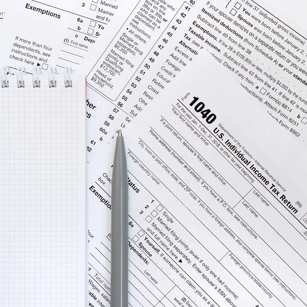 笔和笔记本是位于税表1040美国个人所得税的回报 纳税时间 — 图库照片