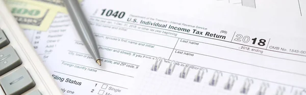 The pen, notebook, calculator, and dollar bills is lies on the tax form 1040 U.S. Individual Income Tax Return. The time to pay taxes