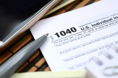 Kalem, defter, smartphone ve dolar faturaları yalanlar üzerine vergi 1040 ABD bireysel gelir vergisi beyannamesi formu var. Vergi ödemek için zaman