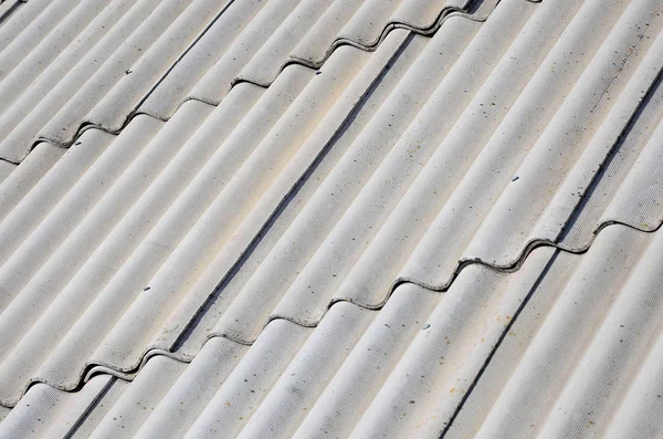 A fragment of a gray slate roof of an old sample made of asbestos material