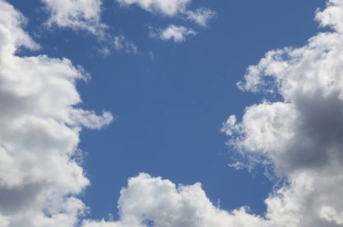 Mavi gökyüzüne bir sürü beyaz bulutlar farklı boyutlarda, bulutsuz çevresini bir çerçeve oluşturma