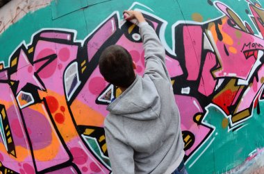Gri kapüşonlu genç bir adam grafiti c pembe ve yeşil boyalar