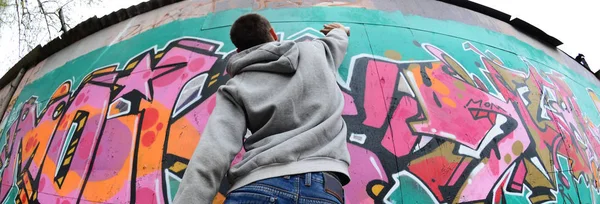 Mladý Muž Šedém Hoodie Maluje Graffiti Růžové Zelené Barvy Zeď — Stock fotografie