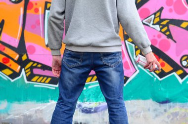 Gri kapüşonlu bir genç grafiti sanatçısı bir duvara yağmurlu havalarda pembe ve yeşil renklerde onun graffiti ile duvara görünüyor. Sokak sanatı kavramı