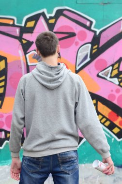 Duvar gri kapüşonlu bir genç grafiti sanatçısı bakar 