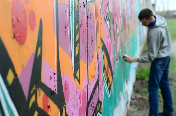 Mladý Muž Šedém Hoodie Maluje Graffiti Růžové Zelené Barvy Zeď — Stock fotografie