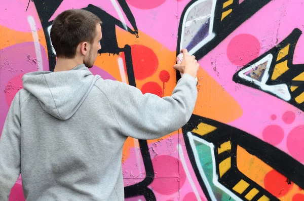 Mladý Muž Šedém Hoodie Maluje Graffiti Růžové Zelené Barvy Zeď — Stock fotografie