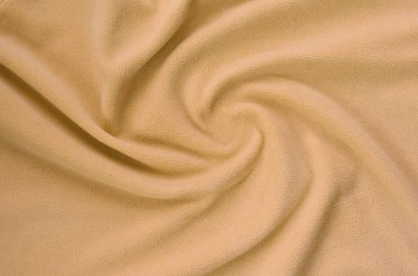 Tüylü turuncu Polar kumaş battaniye. Bir arka plan ışık turuncu yumuşak peluş Polar malzeme bir sürü kabartma kıvrımları ile