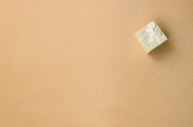 Turuncu küçük bir yay ile bir küçük hediye kutusunda bir battaniye yumuşak ve tüylü ışık turuncu Polar kumaş üzerinde yatıyor. Güzel kız için bir hediye için ambalaj